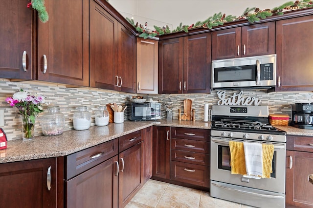 kitchen featuring appliances with stainless steel finishes, light tile patterned flooring, backsplash, and light stone countertops