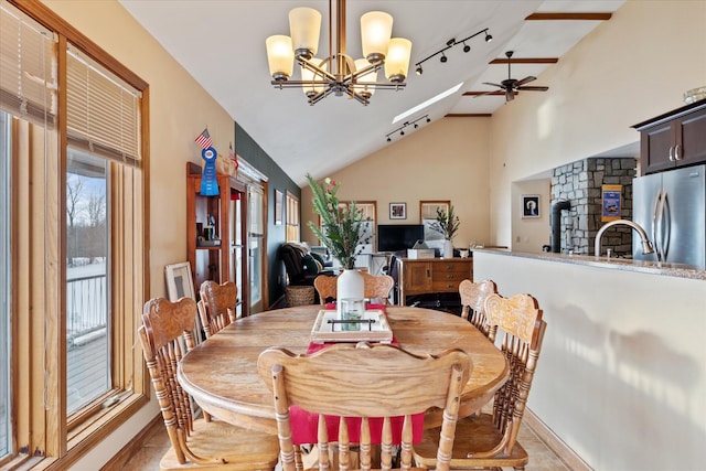 dining space with baseboards, high vaulted ceiling, and ceiling fan with notable chandelier