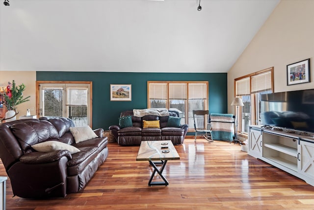 living room featuring high vaulted ceiling and light wood-style floors