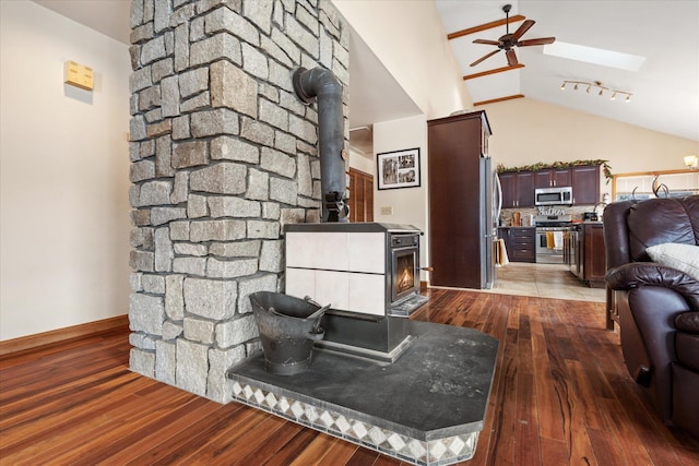 kitchen with open floor plan, stainless steel appliances, wood finished floors, and a wood stove