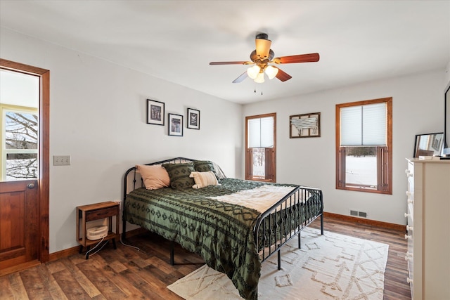 bedroom featuring ceiling fan, wood finished floors, visible vents, and baseboards