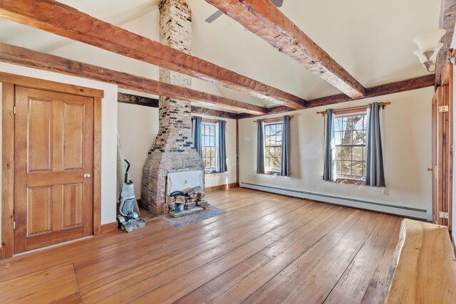 unfurnished living room featuring a baseboard radiator, a wealth of natural light, a wood stove, and hardwood / wood-style flooring
