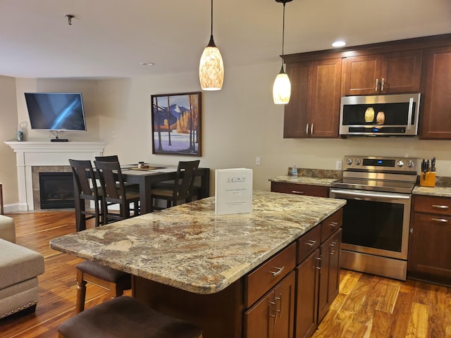 kitchen featuring a center island, stainless steel appliances, wood finished floors, and open floor plan