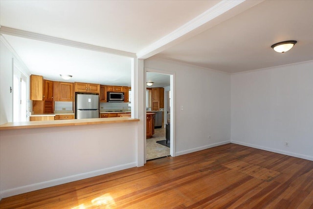 332 Back River Rd, Boothbay, ME 04537 - kitchen with appliances with stainless steel finishes, wood finished floors, brown cabinets, crown molding, and light countertops