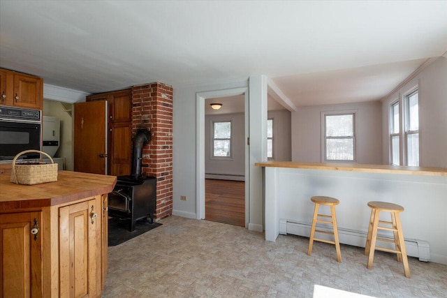 332 Back River Rd, Boothbay, ME 04537 - kitchen featuring black oven, baseboard heating, wooden counters, a baseboard radiator, and light floors