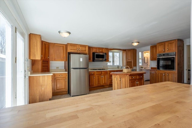 332 Back River Rd, Boothbay, ME 04537 - kitchen with black appliances, brown cabinets, light countertops, and an island with sink