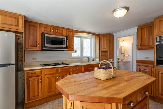 332 Back River Rd, Boothbay, ME 04537 - kitchen with black appliances, butcher block counters, brown cabinets, and a center island