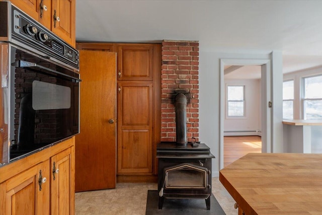 332 Back River Rd, Boothbay, ME 04537 - kitchen featuring oven, a baseboard heating unit, brown cabinetry, and a wood stove