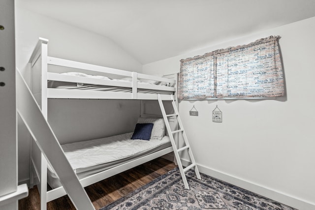 bedroom with vaulted ceiling, baseboards, and wood finished floors