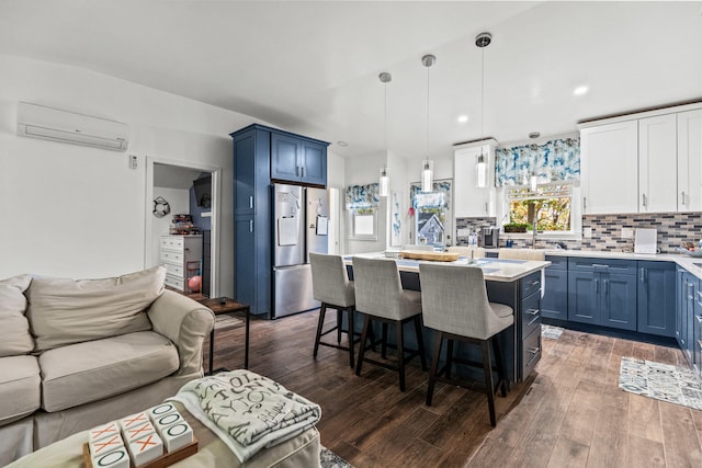 kitchen featuring blue cabinets, a wall mounted AC, open floor plan, stainless steel fridge, and light countertops