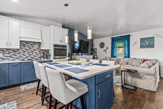 kitchen with dark wood-style floors, blue cabinetry, a breakfast bar area, and oven