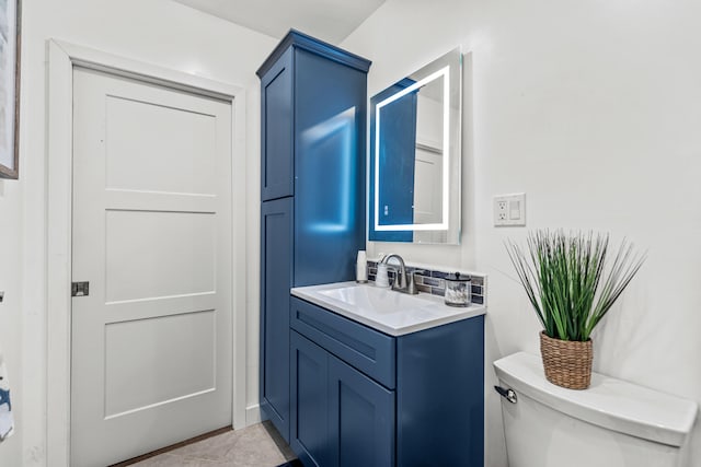 half bathroom with vanity, toilet, and tile patterned flooring