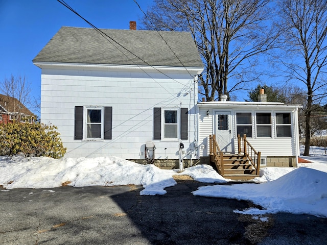 view of front of house featuring roof with shingles and a chimney