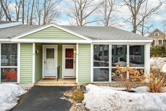 bungalow with driveway, a shingled roof, and a sunroom