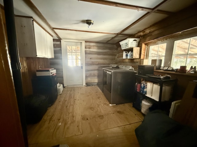 laundry room with light wood-type flooring, laundry area, wooden walls, and washing machine and clothes dryer