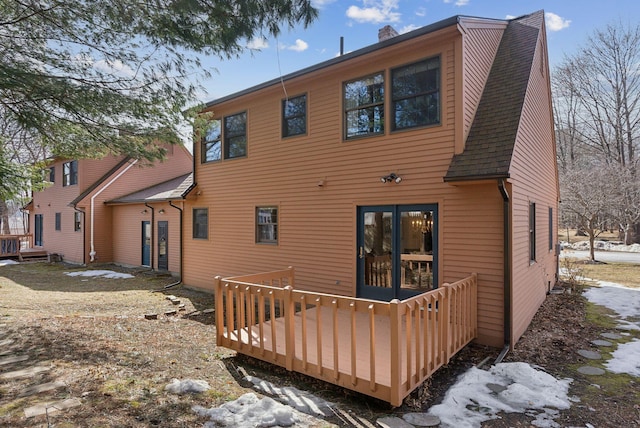 rear view of house featuring a chimney, a wooden deck, and a shingled roof