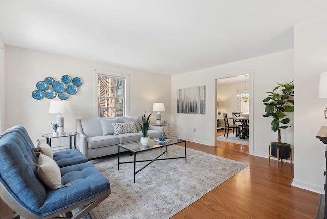 living room featuring baseboards, an inviting chandelier, and wood finished floors