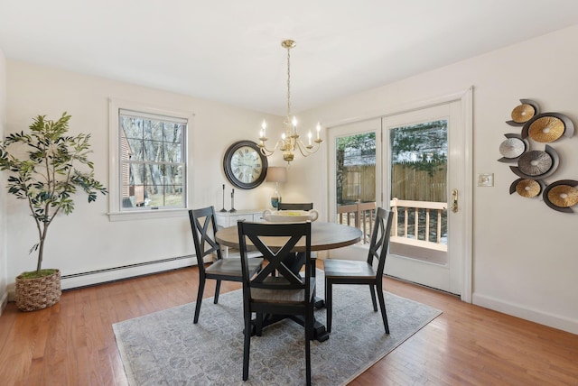 dining room with a baseboard heating unit, baseboards, an inviting chandelier, and wood finished floors