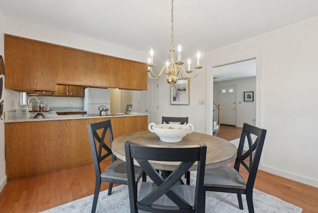 dining area featuring an inviting chandelier, light wood-style flooring, and baseboards