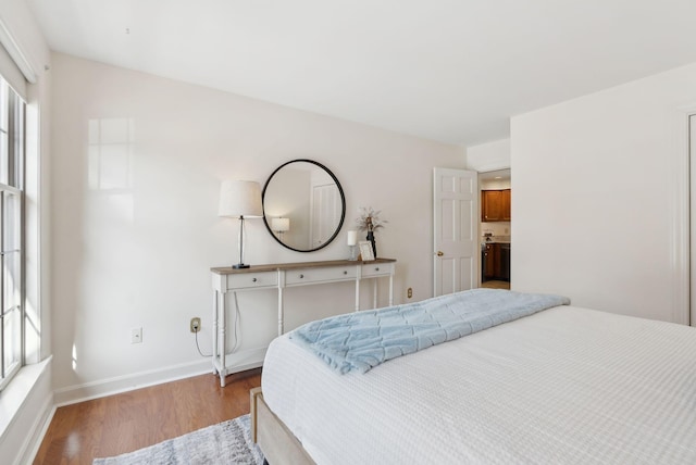 bedroom with baseboards, multiple windows, and wood finished floors