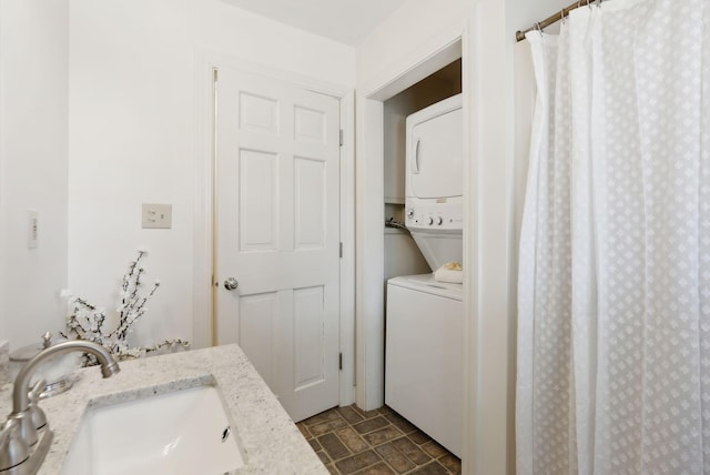 bathroom featuring a sink, stone finish flooring, and stacked washing maching and dryer