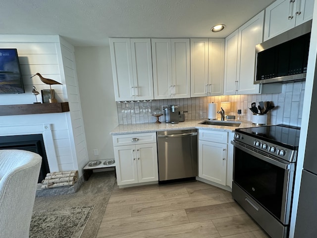 kitchen with stainless steel appliances, light countertops, white cabinetry, and a sink