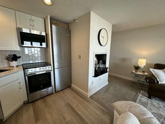 kitchen with stainless steel appliances, light wood-type flooring, and white cabinetry