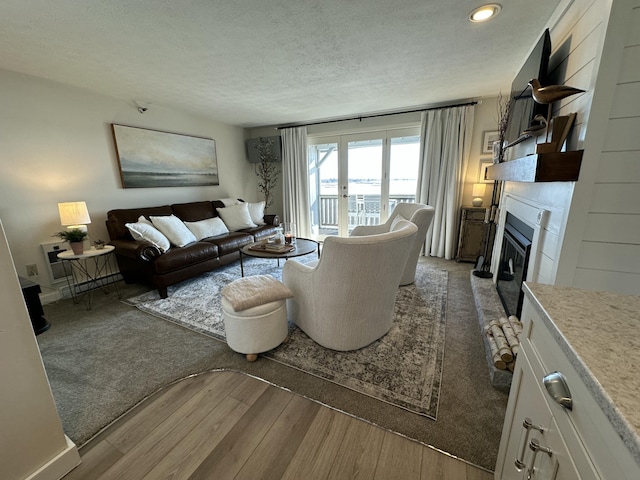 living room with a textured ceiling, a glass covered fireplace, wood finished floors, and baseboards