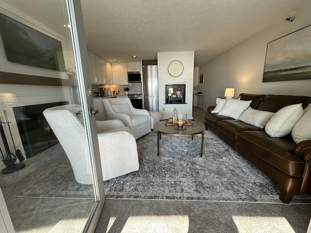 living area featuring a textured ceiling and a glass covered fireplace