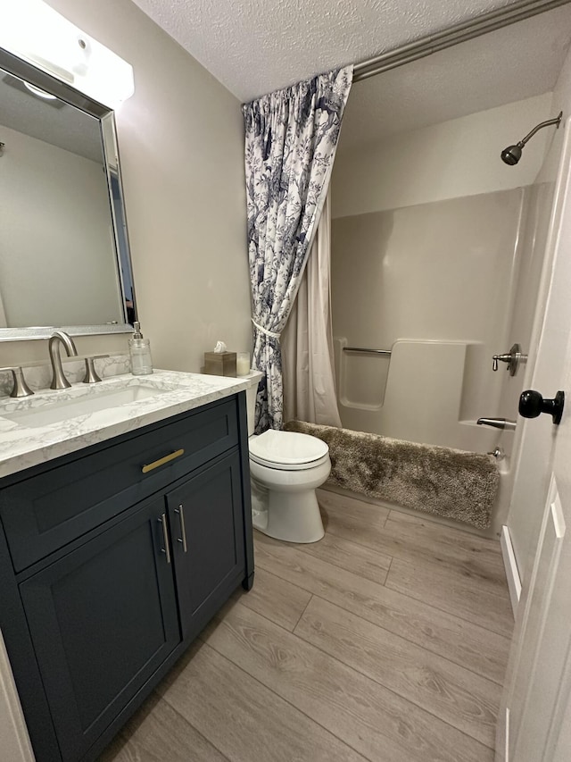 full bath featuring a textured ceiling, toilet, wood finished floors, vanity, and shower / bath combo with shower curtain