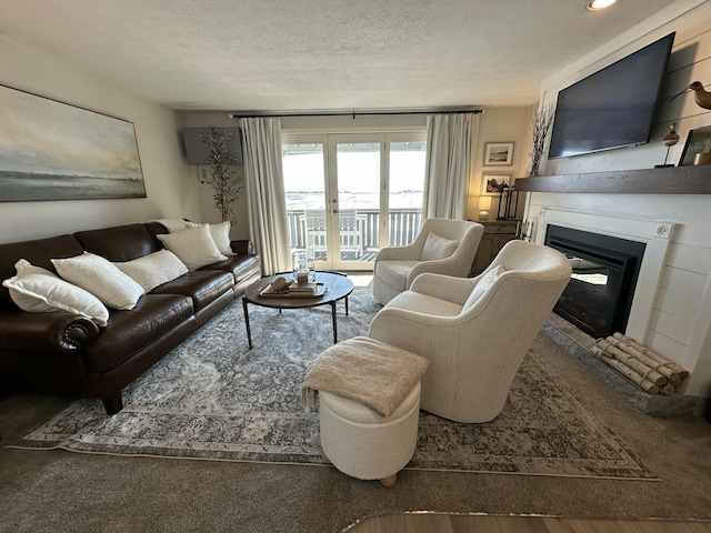 living room with a textured ceiling and a glass covered fireplace