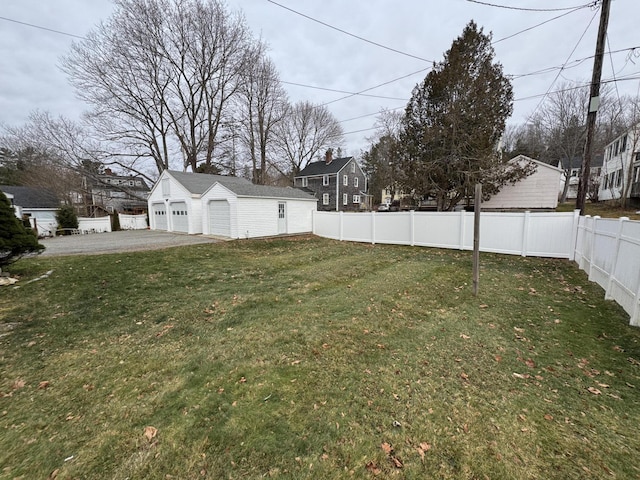 view of yard with a detached garage, fence, and an outbuilding