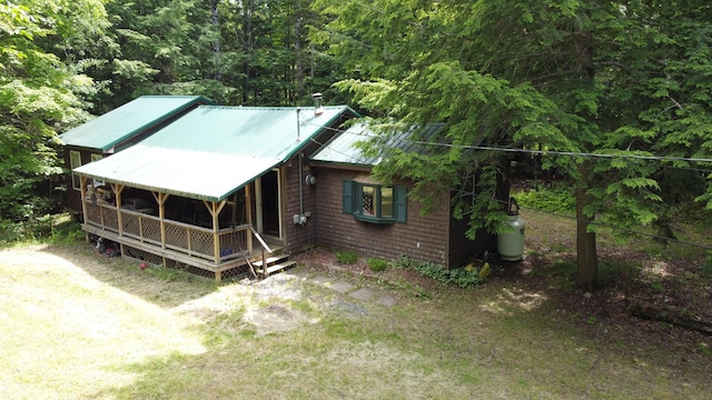 view of front of house featuring dirt driveway, metal roof, and a wooded view