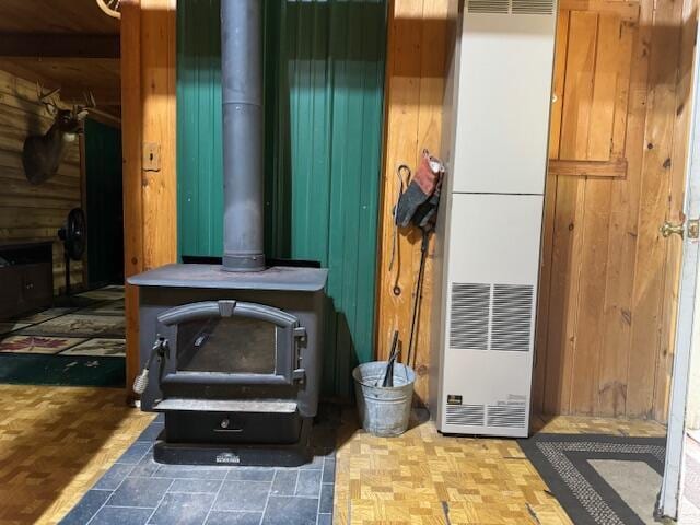 interior details with a wood stove, a heating unit, and wooden walls