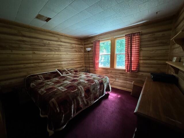 bedroom with rustic walls and dark colored carpet