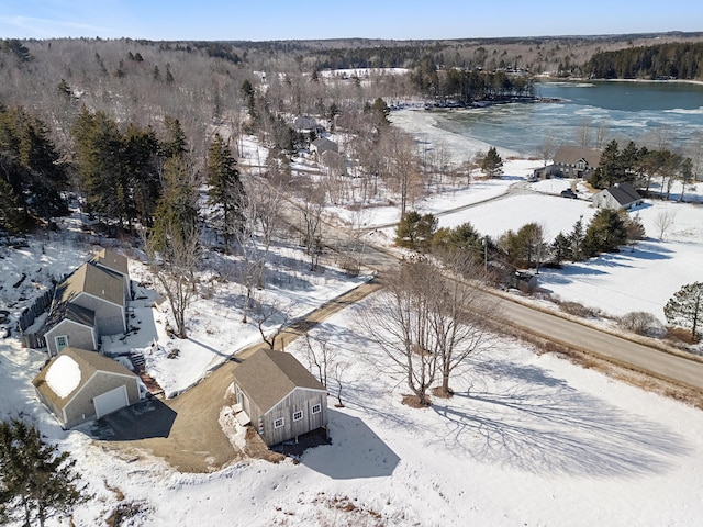 snowy aerial view with a water view and a wooded view