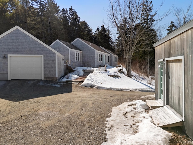 view of snow covered exterior featuring a garage and driveway