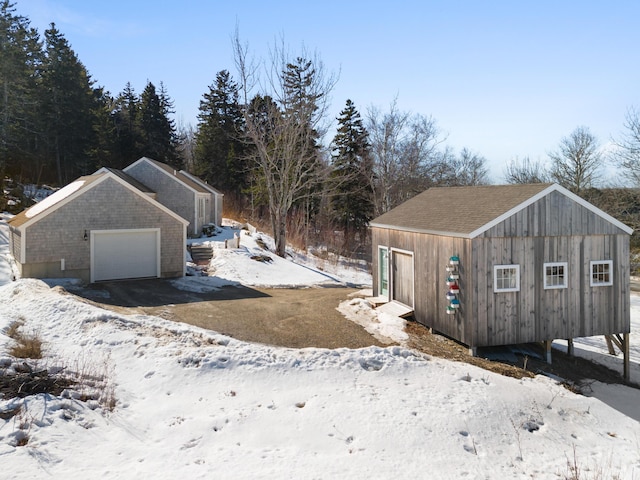 snowy yard featuring a garage and an outdoor structure