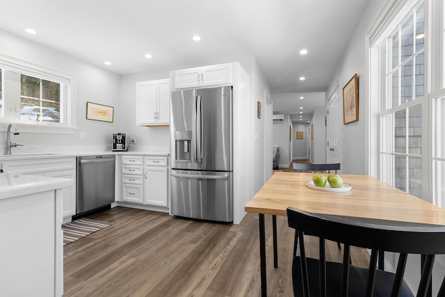 kitchen featuring dark wood-type flooring, stainless steel appliances, white cabinetry, a sink, and recessed lighting