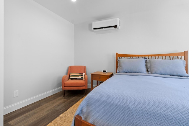 bedroom featuring baseboards, wood finished floors, and a wall mounted air conditioner