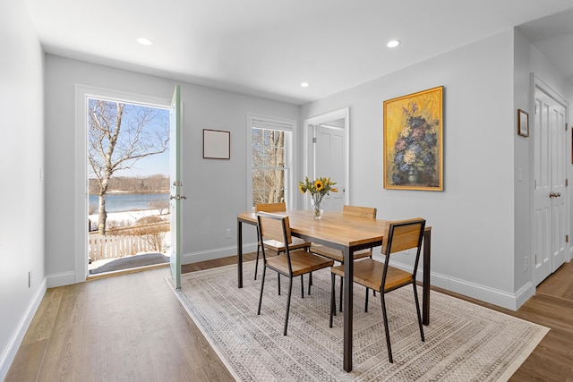 dining space featuring a water view, recessed lighting, wood finished floors, and baseboards