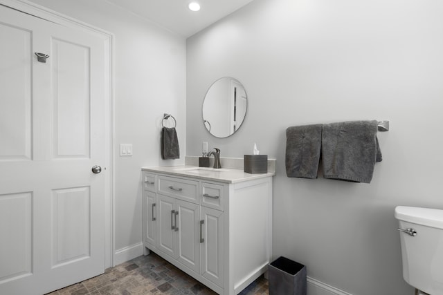 bathroom with toilet, recessed lighting, baseboards, and vanity