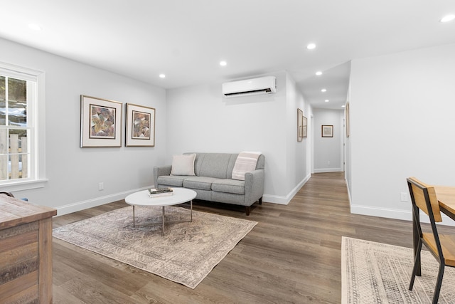 living room with baseboards, wood finished floors, an AC wall unit, and recessed lighting