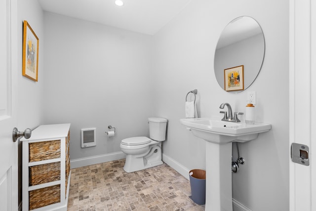 half bathroom featuring heating unit, baseboards, and toilet