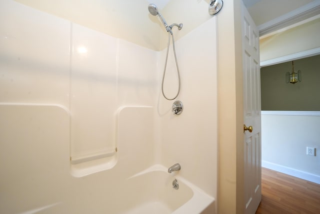 full bath featuring baseboards, shower / washtub combination, and wood finished floors