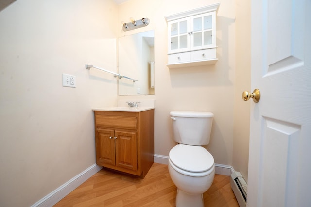 half bath with a baseboard radiator, wood finished floors, toilet, and baseboards