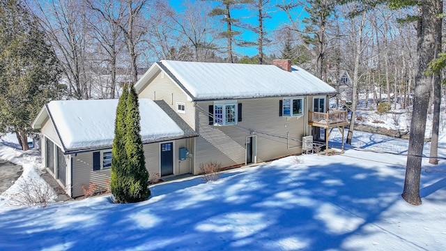 view of snowy exterior featuring a chimney and metal roof