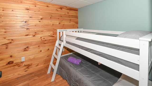 bedroom with wood walls and wood finished floors