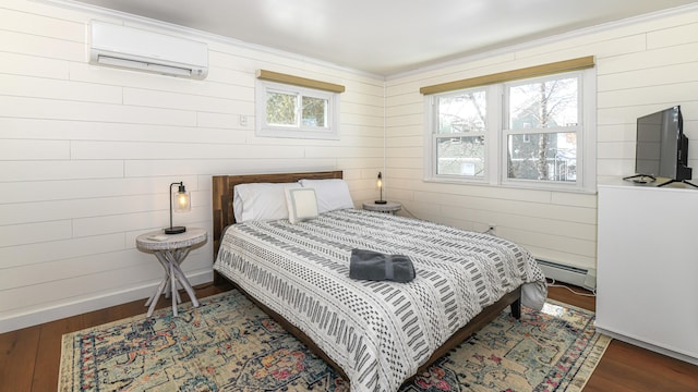 bedroom with a baseboard heating unit, an AC wall unit, baseboards, and wood finished floors