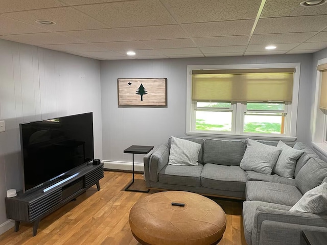 living room with light wood-type flooring, a baseboard radiator, a paneled ceiling, and baseboards